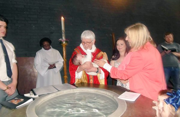 baptism at font with vicar and baby
