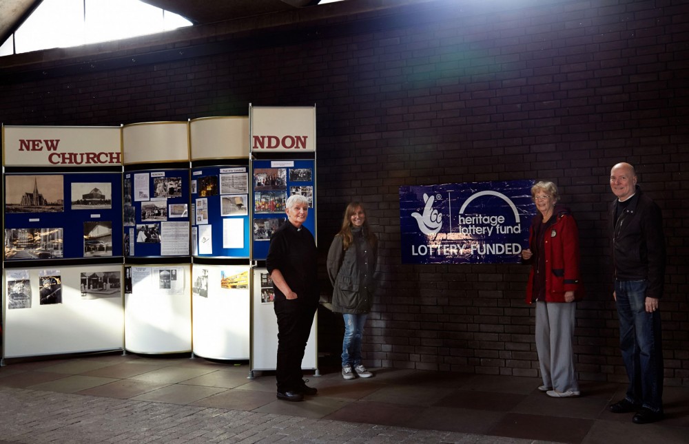 vicar with guests in front of display board